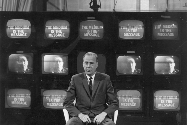 Marshall McLuhan, in front of bank of TV screens